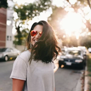 girl wearing sunglasses facing away from a sunset